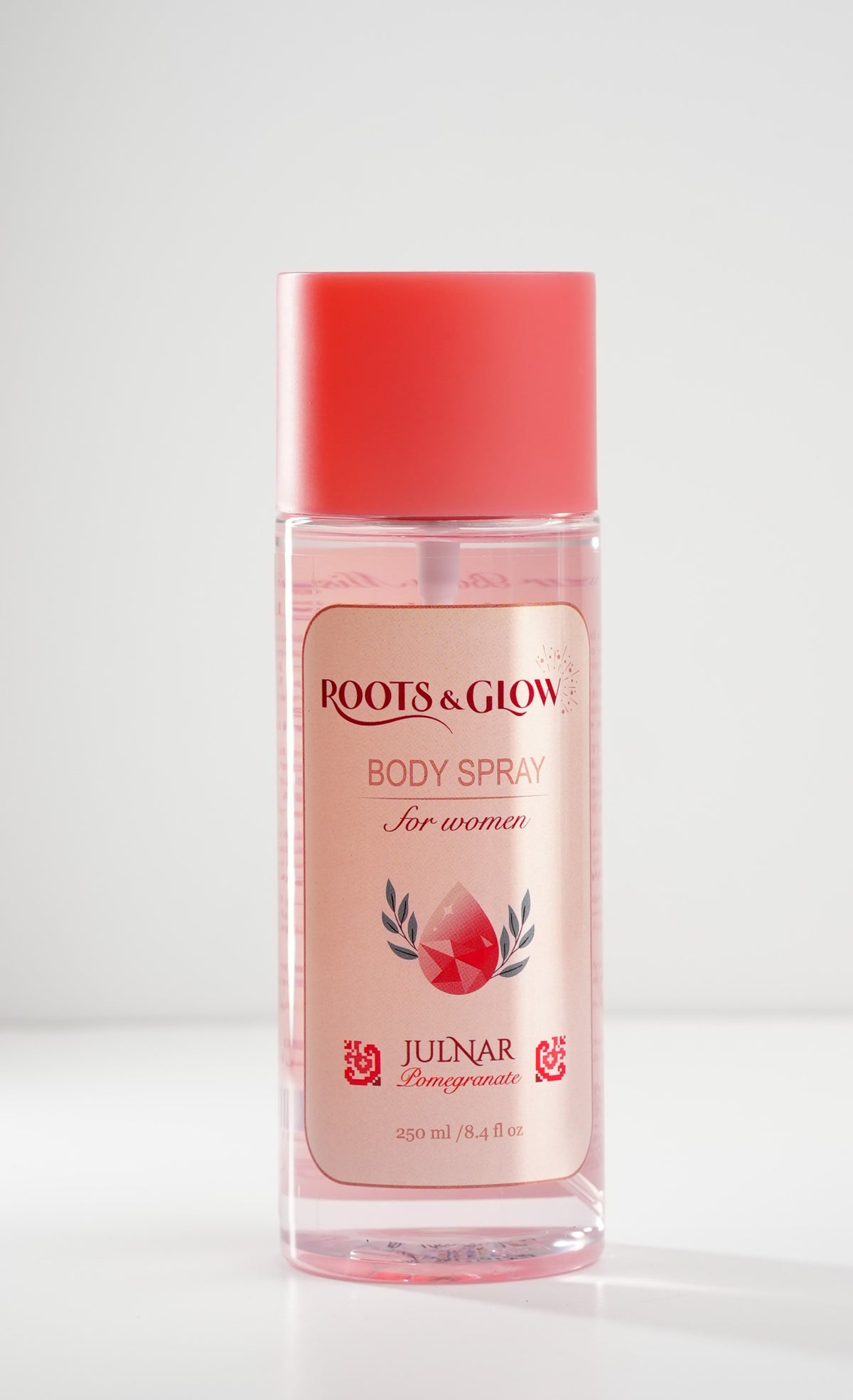 Julnar Women's Body Mist, a clear glass bottle of pale pink liquid with a coral cap